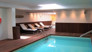 A swimming pool area with lounge chairs and a wooden deck.