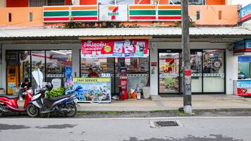 A 7-Eleven convenience store with a taxi service sign, a motorcycle parked in front, and a 7-Eleven sign on the building.