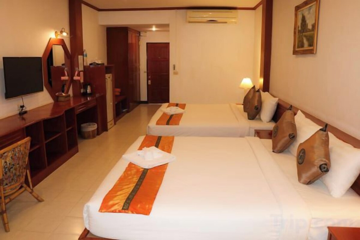 A hotel room with two beds, a desk, a television, and a mirror.
