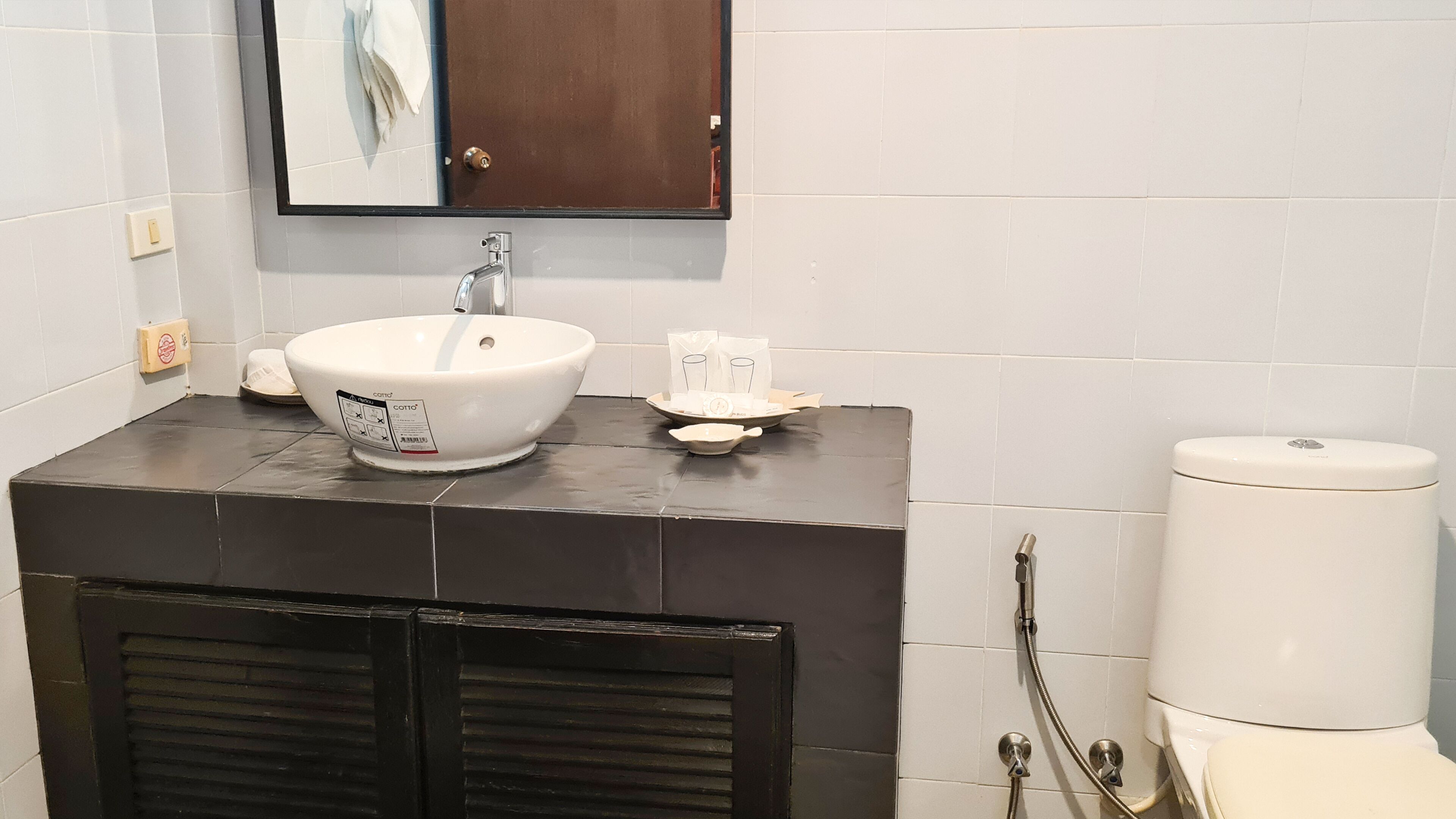 Une salle de bain avec un lavabo blanc, un miroir, un porte-serviettes, des toilettes et une douche.