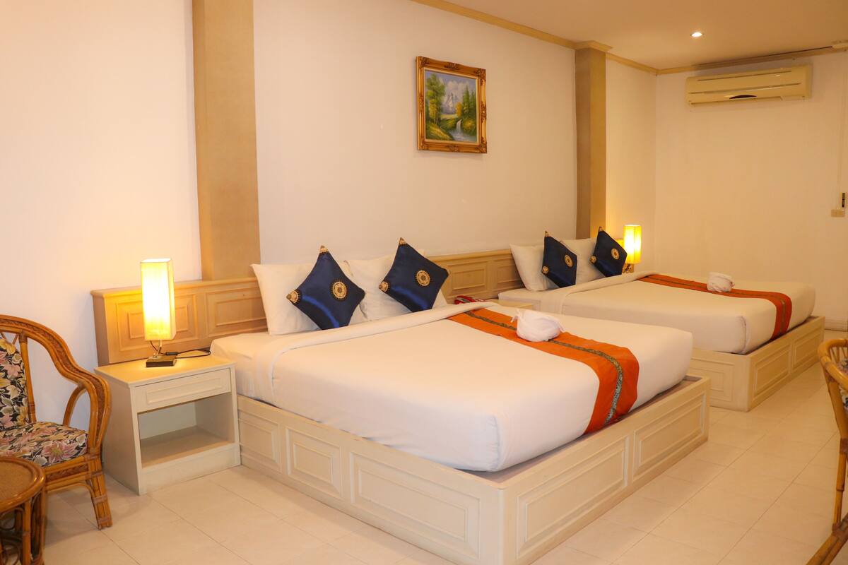 A hotel room with two beds, nightstands, a chair, and a painting on the wall.