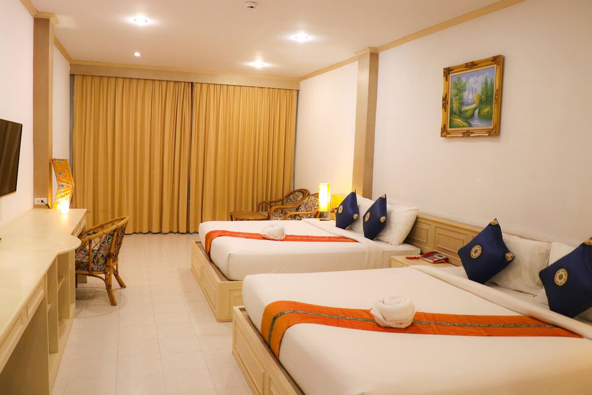 A hotel room with two beds, a desk, a chair, and a painting on the wall.