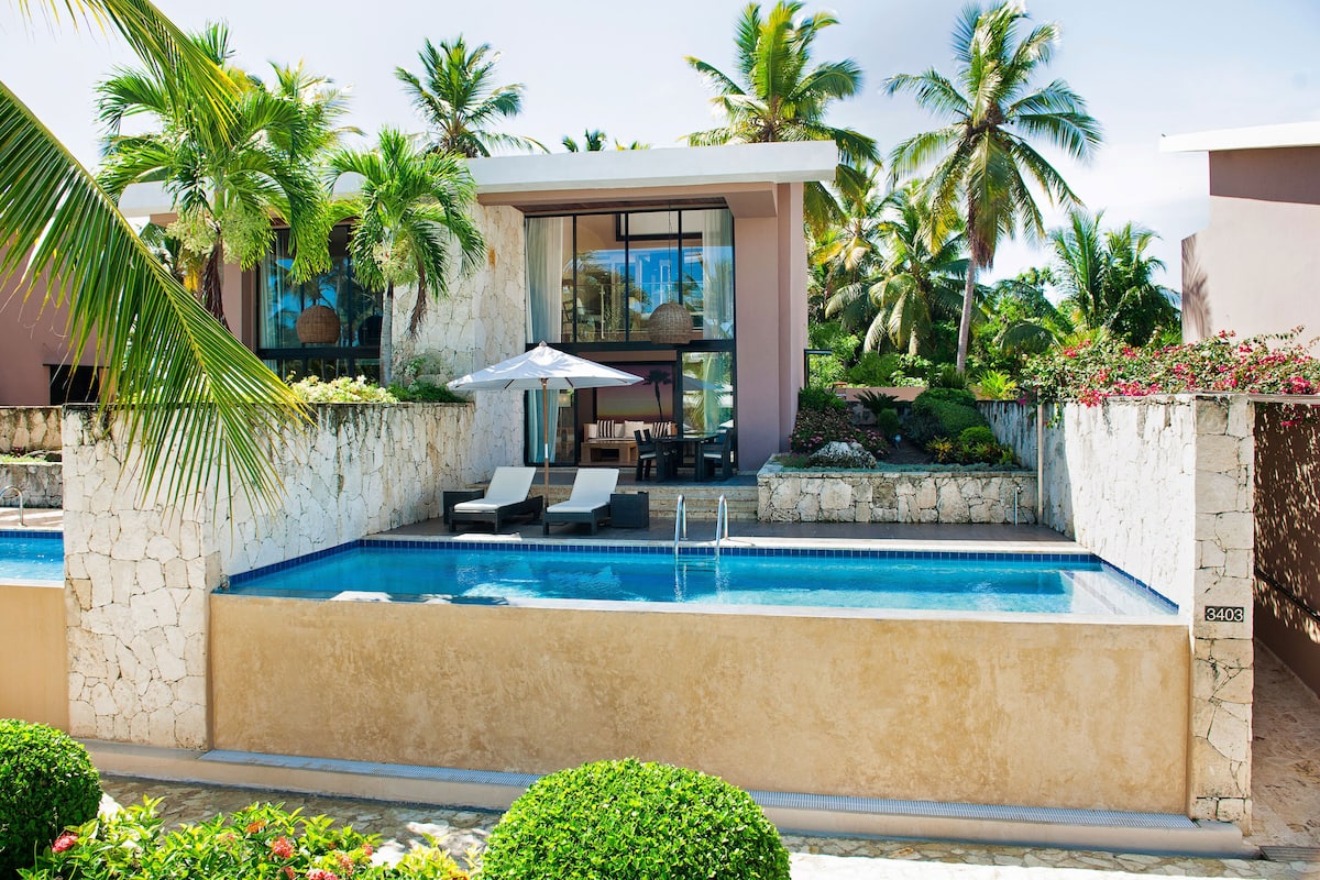 A modern pool area with lounge chairs, a table, and a large umbrella.