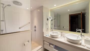 A modern bathroom with a walk-in shower, a large mirror, and a white sink.