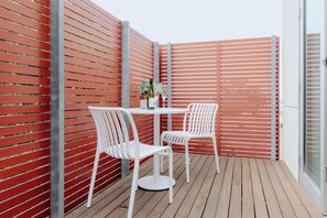 A patio area with a white table and chairs, a bottle of wine, and a glass. - Punthill Williamstown (Williamstown)
