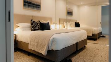 A modern hotel room with a large bed, a bedside table, a mirror, and a carpeted floor.