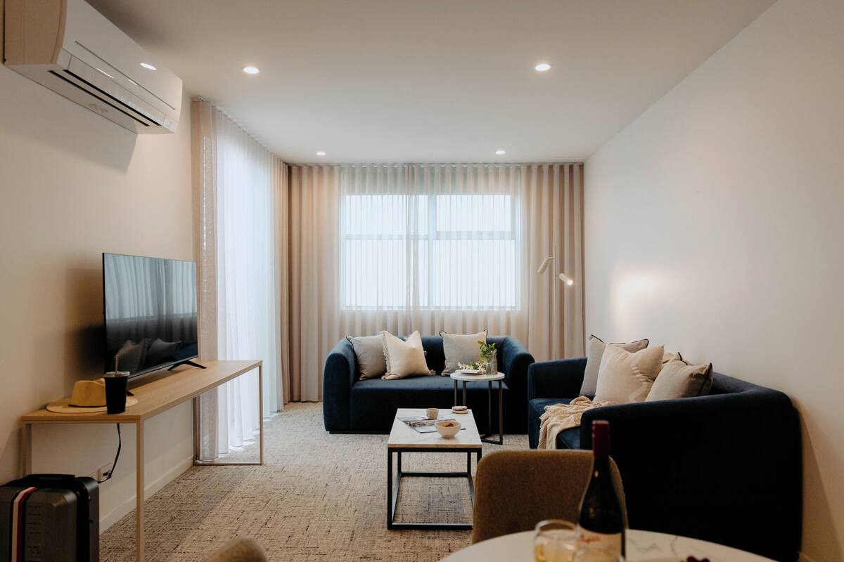 A modern living room with a sofa, a coffee table, a TV, and a small side table.