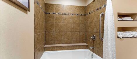 Un baño con bañera, ducha y paredes de azulejos.