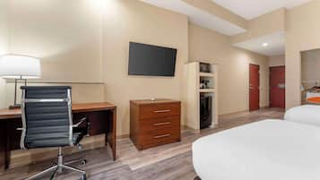 A hotel room with a desk, chair, dresser, TV, and two beds.