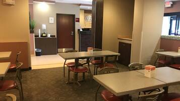 Un hall d’hôtel avec plusieurs tables et chaises, un comptoir de réception et un panneau indiquant clairement la sortie.