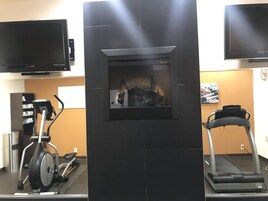 Uma academia com equipamentos de ginástica, incluindo esteira e elíptico.