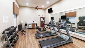 Et fitnesscenter med løbebånd, håndvægte og træningsudstyr.