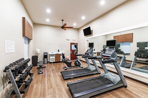Een fitnessruimte met loopbanden, gewichten en trainingsapparatuur.