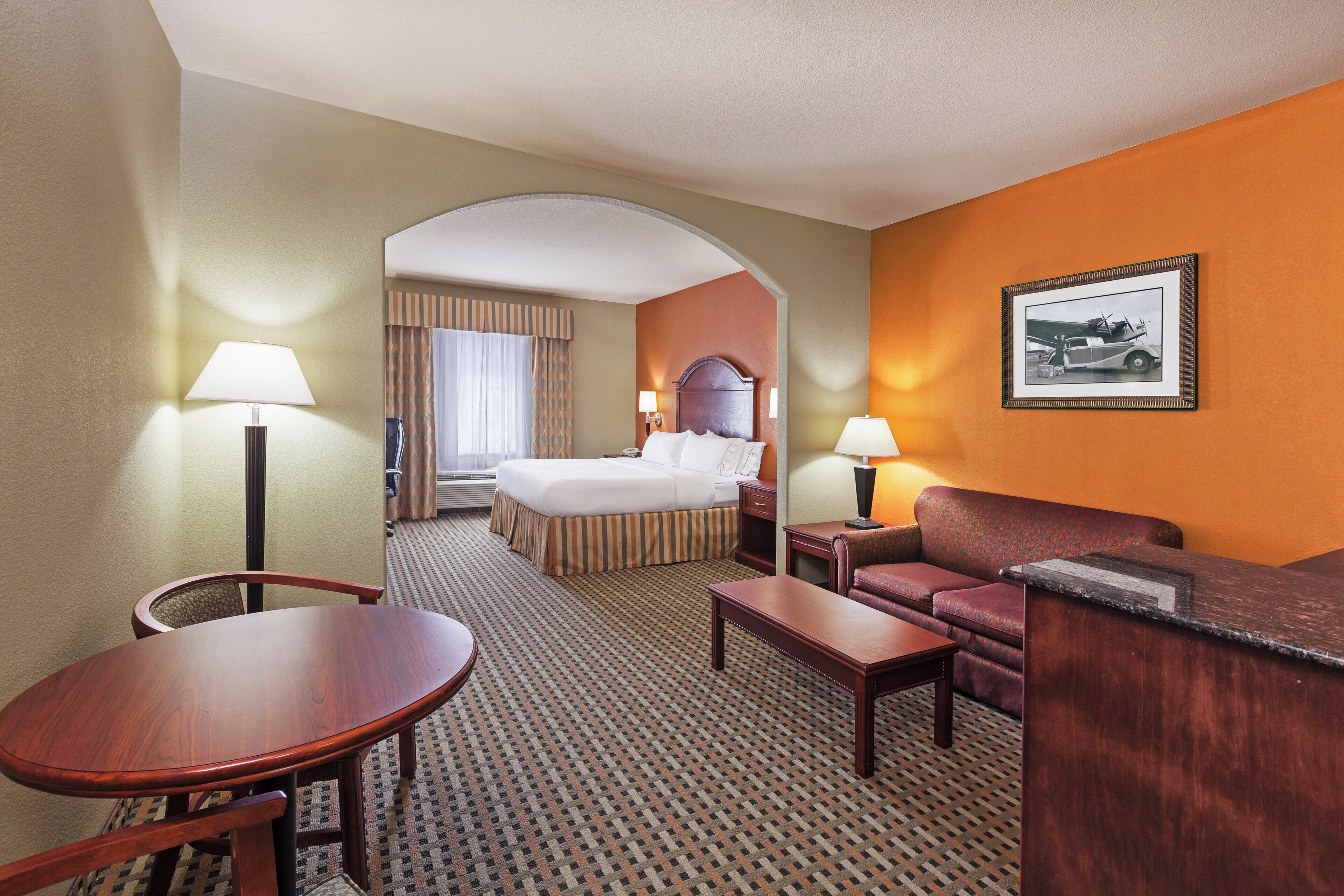 Ein Hotelzimmer mit einem Bett, einem Schreibtisch, einer Couch und einem Esstisch.