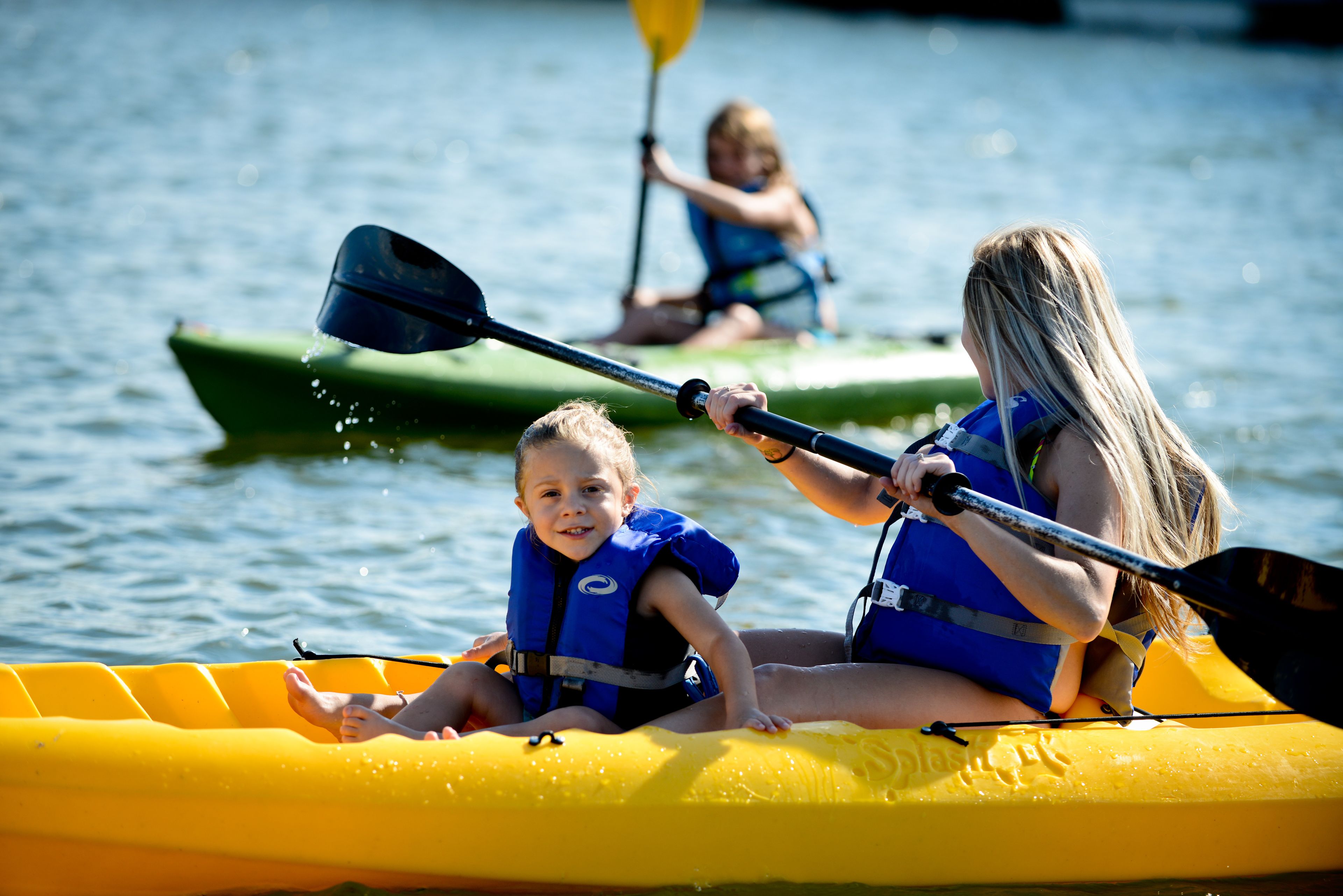 A group of people in a yellow raft on a body of water, wearing life jackets.