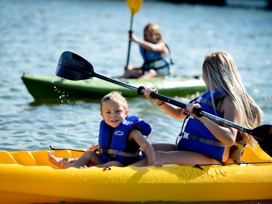 A group of people in a yellow raft on a body of water, wearing life jackets.