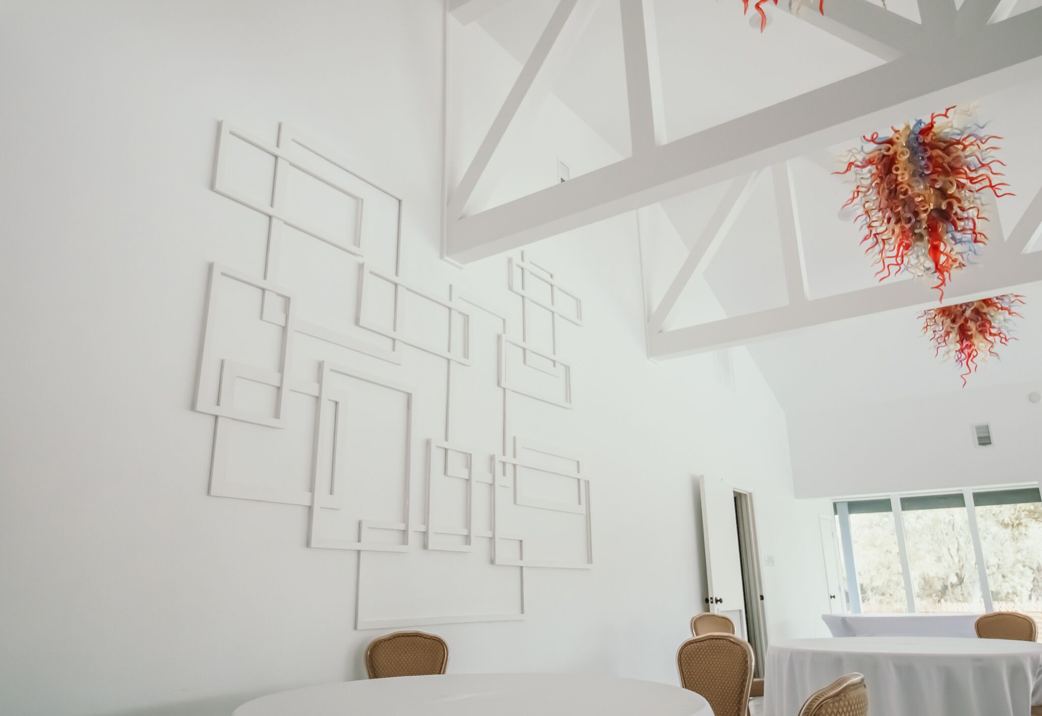 A modern interior with geometric wall art, a dining area, and a large window.