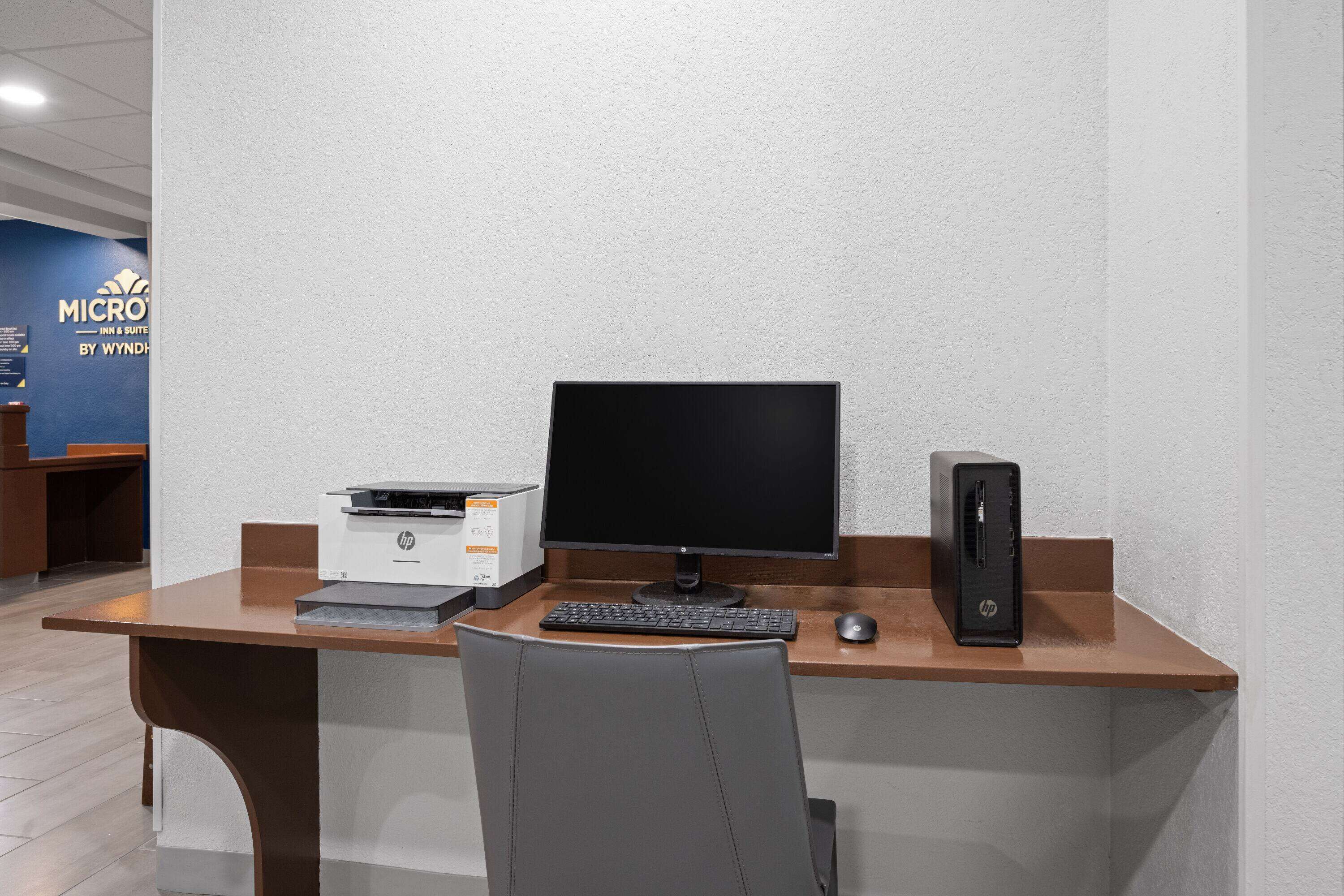 A hotel room with a desk, a computer, and a printer.