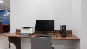 A hotel room with a desk, a computer, and a printer.