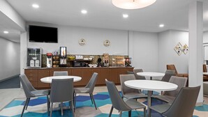 Una cocina moderna con televisión de pantalla plana, cafetera y refrigerador.