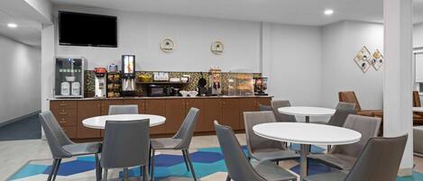 A modern kitchen area with a flat-screen TV, a coffee machine, and a refrigerator.