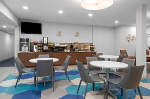 A modern kitchen area with a flat-screen TV, a coffee machine, and a refrigerator.