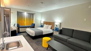 Una habitación de hotel con una cama, un sofá, un escritorio con lavabo y una mesita.