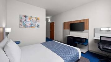 A hotel room with a bed, a desk, a television, and a microwave.