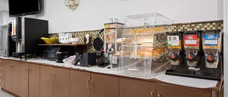 A breakfast bar with a coffee machine, cereal dispensers, and a fruit bowl.