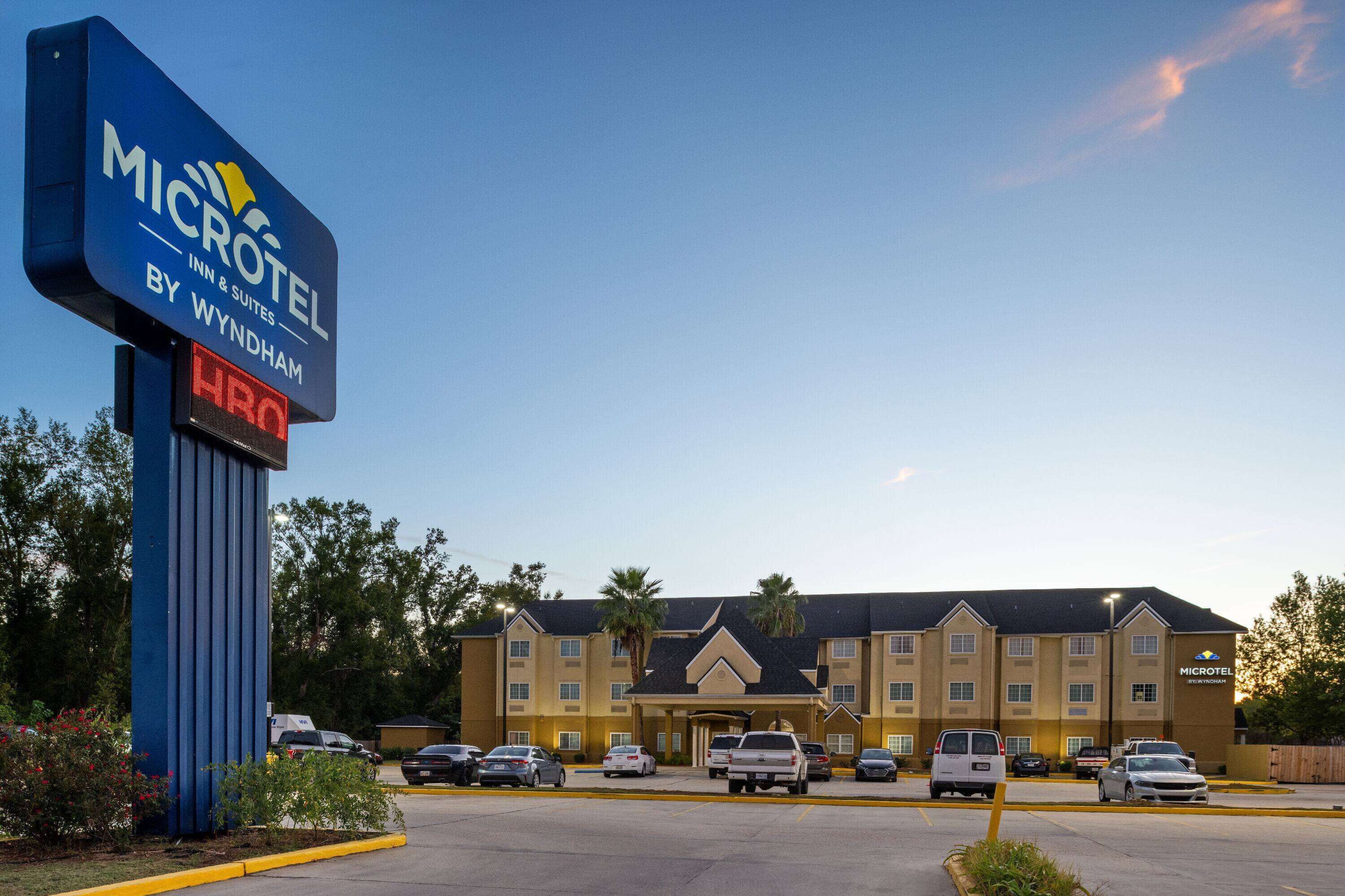 Un bâtiment de la chaîne Microtel Inn & Suites, avec un parking, plusieurs voitures et un ciel dégagé.
