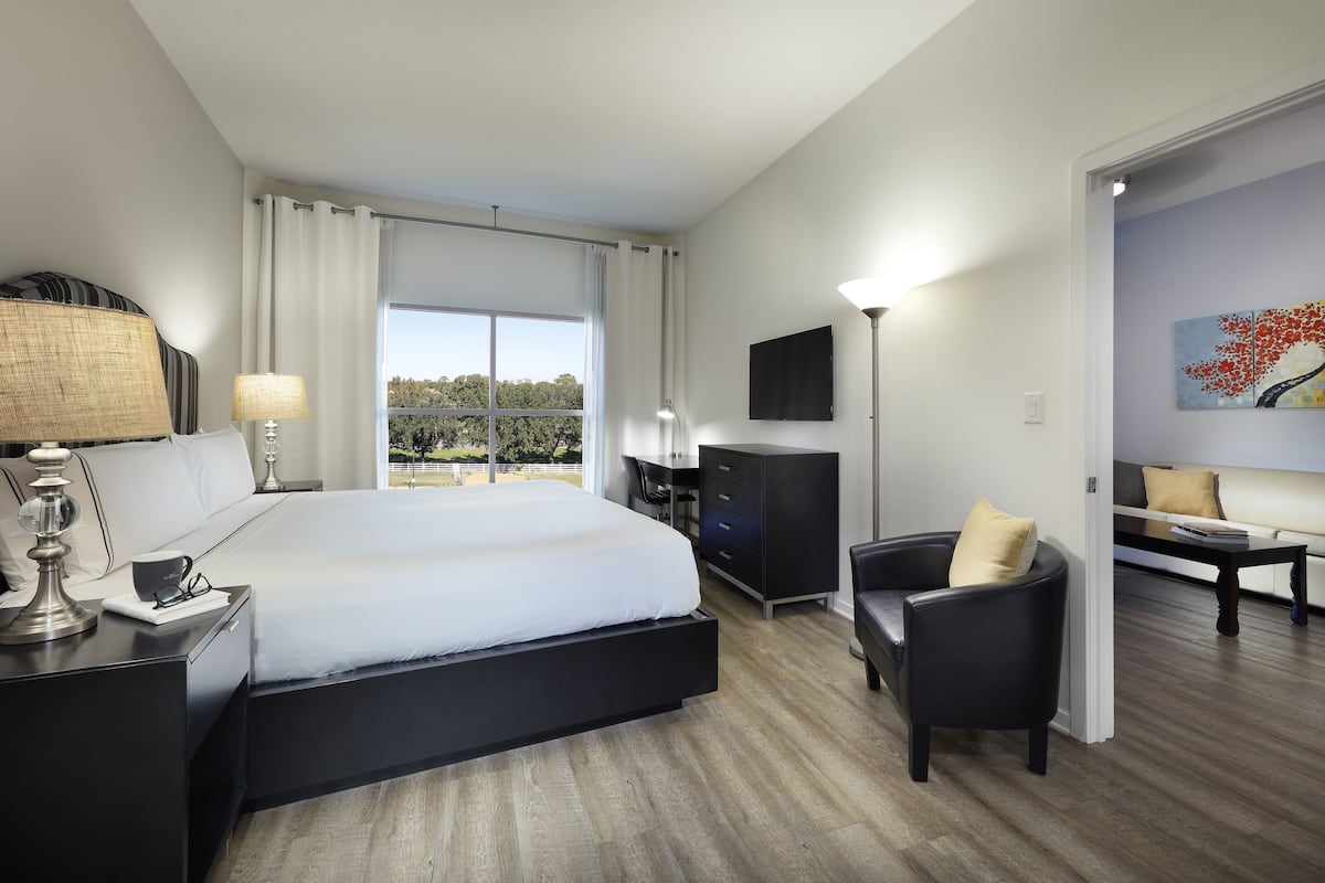 Quarto de hotel moderno com uma cama grande, uma mesa, uma cadeira e um sofá.