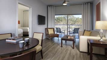 Una sala moderna con una mesa redonda, dos sillones, un sofá y un balcón con mobiliario exterior.