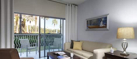 A room with a sofa, a coffee table with a book and a mug, a lamp, and a painting on the wall.