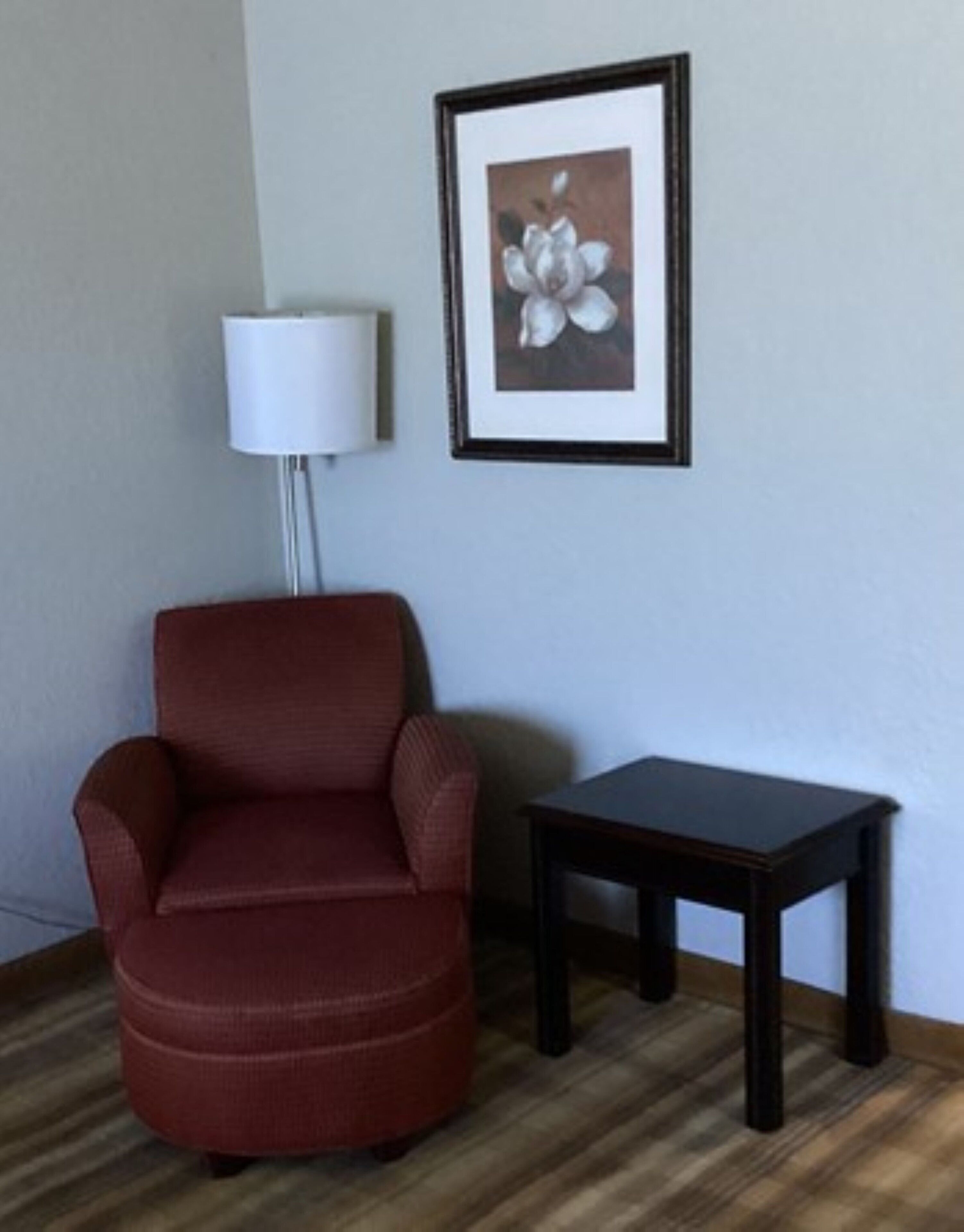 Una poltrona rossa, un tavolino e un quadro incorniciato appesi al muro.