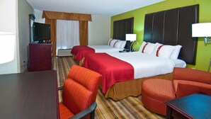 Quarto de hotel com duas camas, televisão, escrivaninha e uma cadeira.