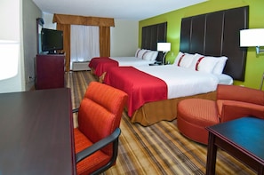 A hotel room with two beds, a TV, a desk, and a chair.
