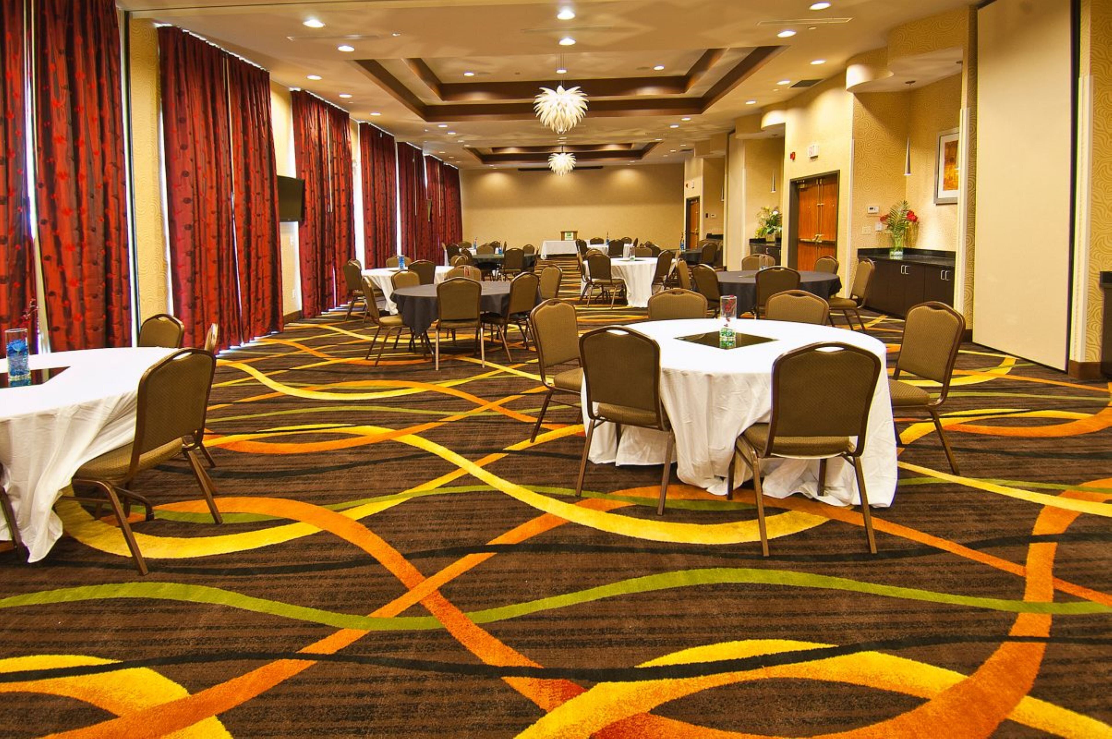 A conference room with tables and chairs, a patterned carpet, and a chandelier.