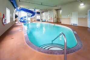 An indoor swimming pool with a blue slide, a lifeguard stand, and a clear view of the pool's edge.