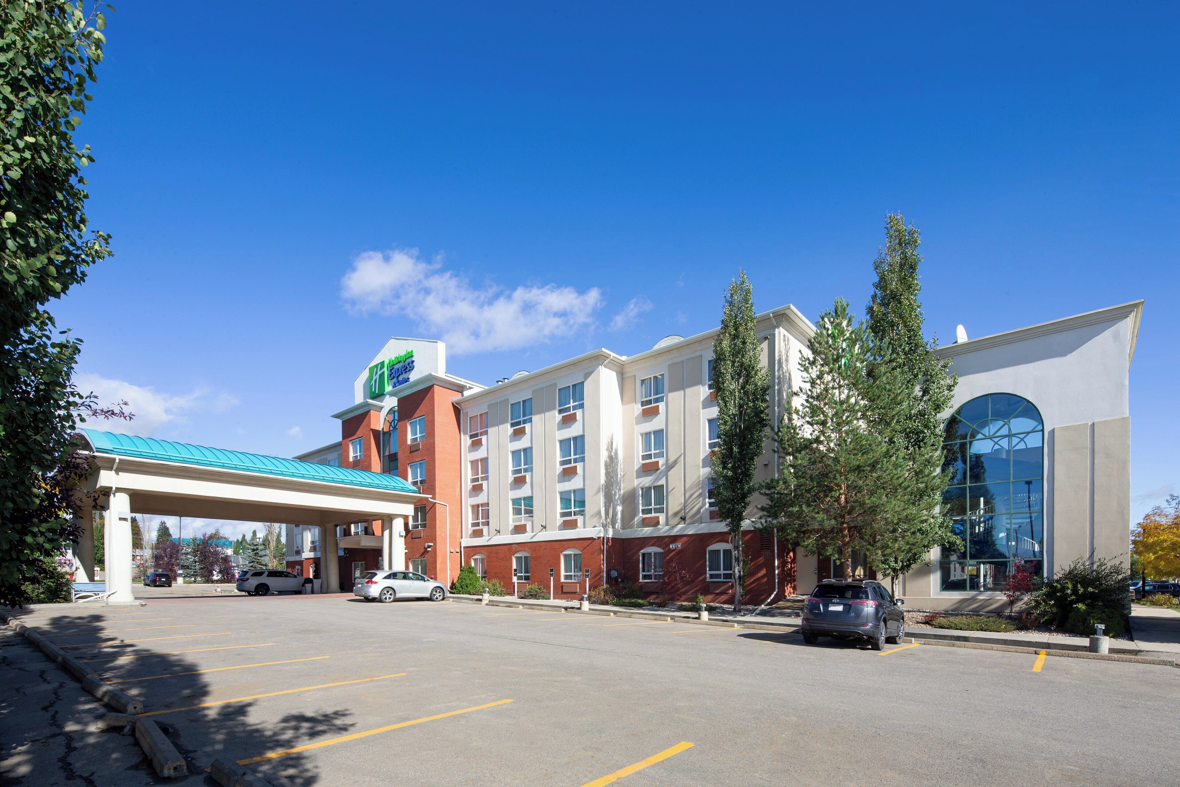 A hotel with a parking lot, a gas station, and a large building with a glass facade.
