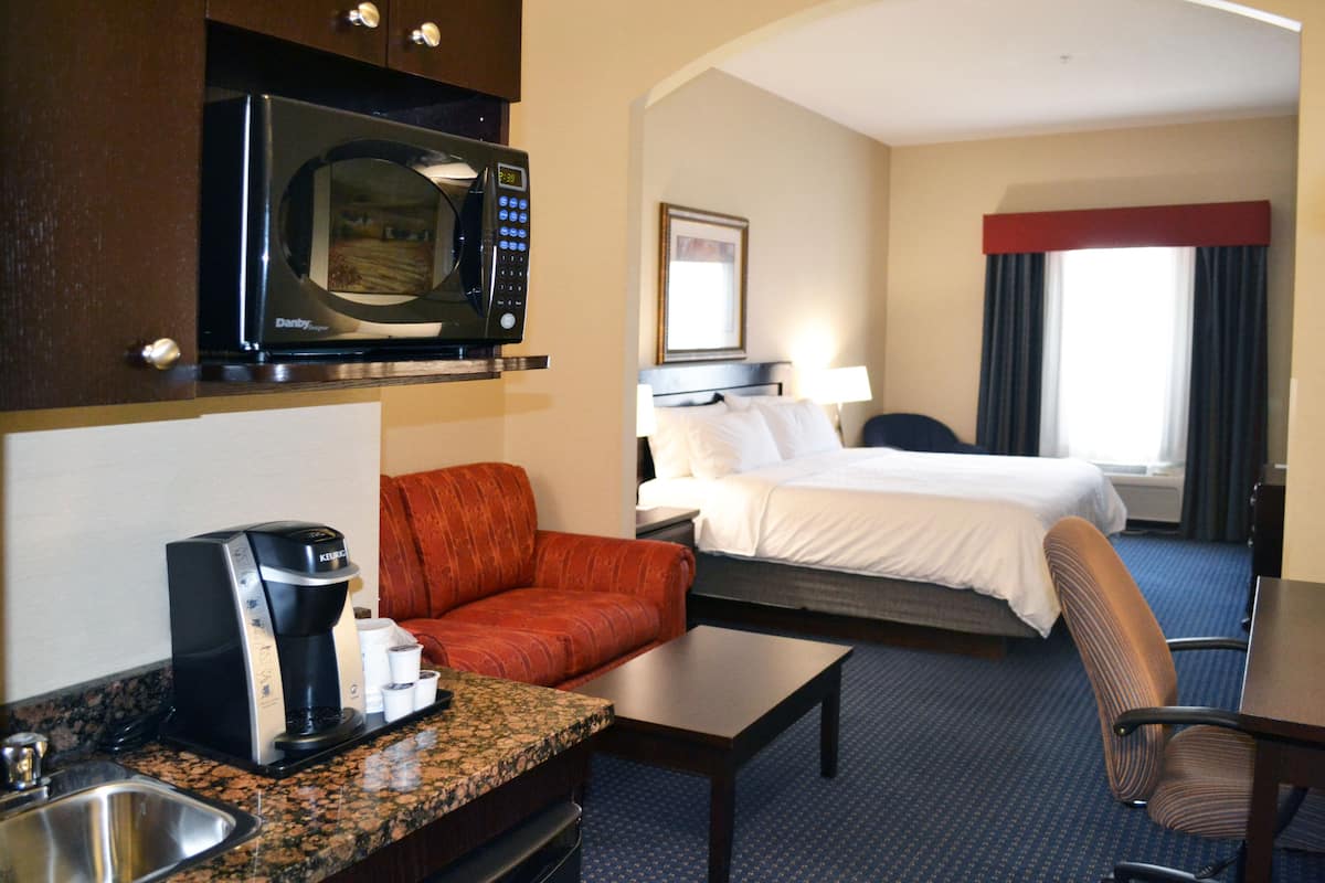 Ein Hotelzimmer mit einer Küchenzeile, einem Bett, einem Schlafsofa, einem Schreibtisch und einem Stuhl.
