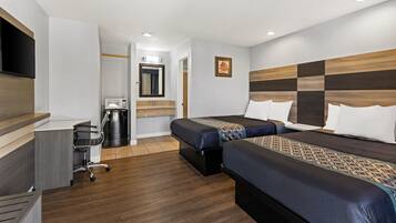 A hotel room with two beds, a desk, a chair, a TV, a microwave, and a trash bin.