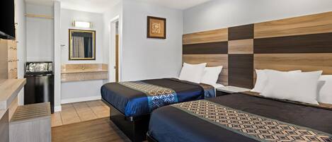 A hotel room with two beds, a wooden headboard, a small desk, and a mirror.