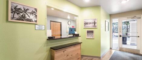 A reception area with a check-in counter, a wooden cabinet, a mirror, and framed pictures on the wall.