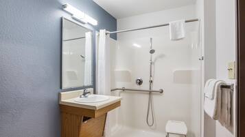 A modern bathroom with a sink, mirror, shower, and a small stool.