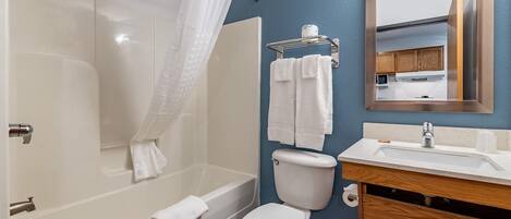 A bathroom with a bathtub, toilet, sink, and a mirror.