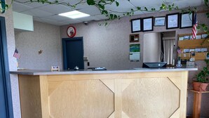 Un comptoir d’accueil avec un revêtement en bois, une horloge, des certificats encadrés et un drapeau américain.