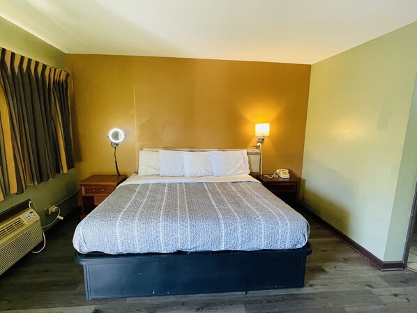 A hotel room with a bed, bedside lamps, a telephone, and a wall-mounted heater.