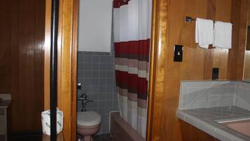 A bathroom with a wooden floor, a toilet, a bathtub, and a sink.