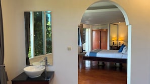 Ein Hotelzimmer mit großem Fenster, Waschbecken, Bett und Holzboden.