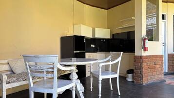 A dining area with a table and chairs, a sofa, a kitchen with appliances, and a fire extinguisher.